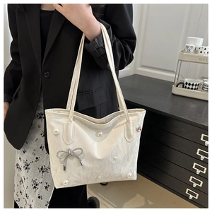 Détail du sac cabas blanc avec perles élégantes et pendentif nœud strass sur cuir souple