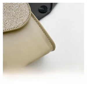 Detail of beige leather crossbody bag with shimmering rhinestone embellishments and stitching