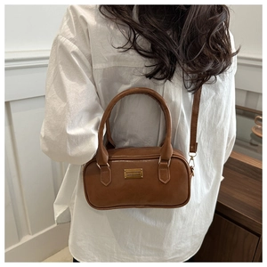 Close-up of brown leather bowling bag with gold hardware and a detachable strap