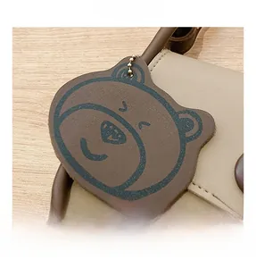 Detail of a brown leather bear charm and contrast stitching on a chic shoulder bag