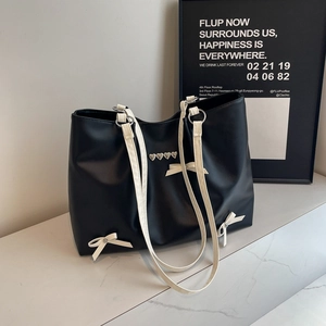Chic black PU tote bag with heart rivets and white ribbon bows on marble surface
