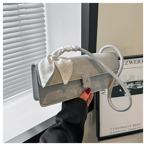 Detail of silver metallic shoulder bag with scarf-wrapped handle and rhinestone buckle
