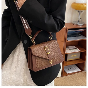 Close-up of brown woven texture bag with gold clasp and jacquard shoulder strap