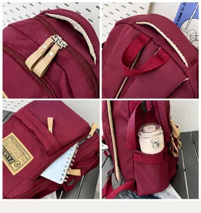Detail view of burgundy backpack showing multi-pocket storage and durable zippers