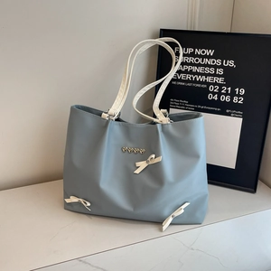 Chic light blue tote bag with white bows and silver heart buckles on marble surface