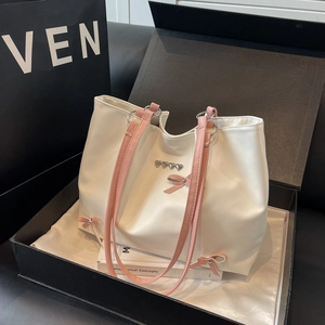 White leather tote bag with pink bow accents and heart metal buckles in a gift box