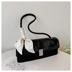 Detail view of black velvet shoulder bag featuring a diamond buckle and silk scarf accent