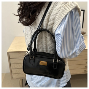 Detail of a chic black bowling bag with gold hardware shown on a model for daily use