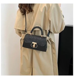 Side view of black sequined crossbody bag with gold lock on beige trench coat