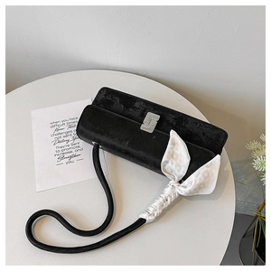 Detail of black velvet shoulder bag with silver buckle and silk scarf handle detail