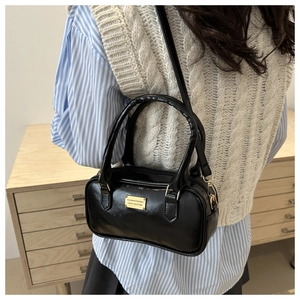 Detail view of black PU leather bowling bag with gold hardware worn by a model