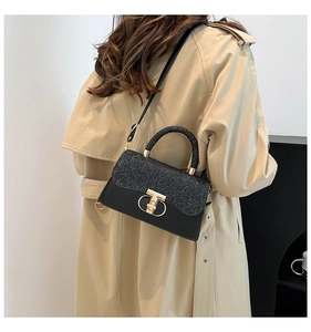 Detail of black sequin chain bag featuring gold T-lock shown with a classic trench coat