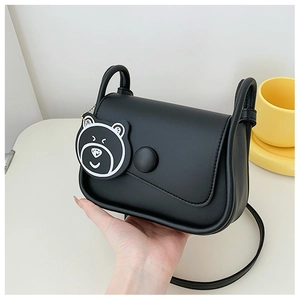 Detail of black faux leather crossbody bag with cartoon bear charm and magnetic flap