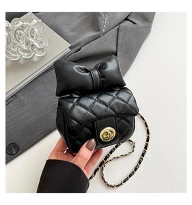 Detail of black quilted mini bag featuring a gold twist lock and a large stylish bow accent