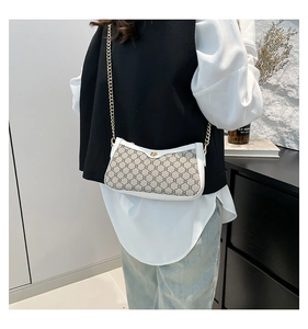 Detail of grey patterned crossbody bag with white leather trim and gold chain strap