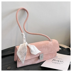 Detail of pink matte handbag featuring a curved cylindrical strap and geometric silk scarf