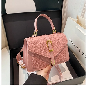 Detail of crossbody bag with woven texture, gold lock, and stylish jacquard strap