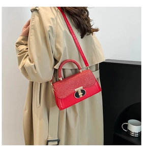 Detailed view of red chain bag with glitter patchwork and golden clasp worn with a trench coat