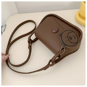 Detailed view of brown square crossbody bag featuring matte leather and bear charm