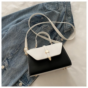 Détails d'un sac bicolore avec fermoir doré posé sur une veste en denim
