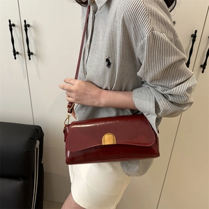 Fashionable burgundy leather underarm bag with vintage gold buckle on casual model