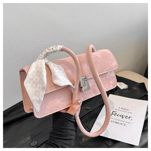 Detail of pink faux suede handbag with sparkling S-shaped buckle and silk scarf on handle