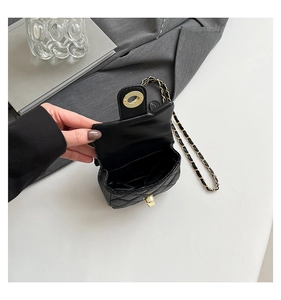 Detail showing the inner storage space and gold twist lock of a black quilted chain bag