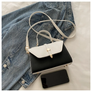 Détail du sac bandoulière en cuir noir et blanc avec fermoir rond doré et garnitures en métal