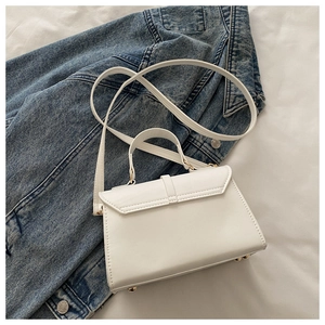 Détail du sac à bandoulière en cuir blanc avec rabat enveloppe et clous dorés à la base