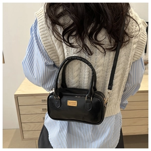 Rear view of model carrying a vintage black bowling bag with gold hardware and PU leather