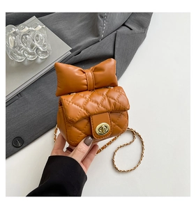 Close-up of caramel quilted leather chain bag with a decorative oversized bow and gold lock