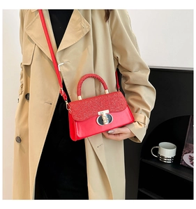 Detail of red small flap bag with glitter finish and golden oval twist-lock on a model