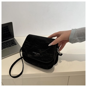 Gros plan sur un sac selle noir plissé avec logo fashion trend sur un bureau blanc