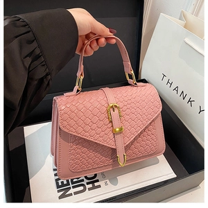 Detail of light pink woven texture handbag with golden U-shaped buckle in a luxury gift box