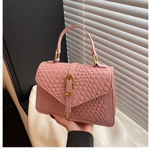 Detail of pink woven texture on women's handbag with golden metallic buckle