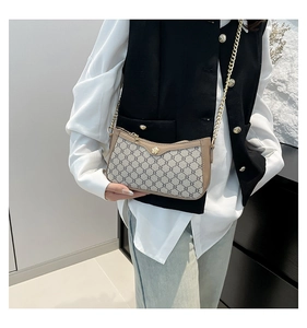 Detail of trendy monogram PU leather crossbody bag with gold chain strap on a model