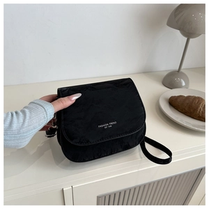 Vue détaillée du sac besace noir plissé avec texte mode dans un décor minimaliste
