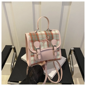 Close-up of pink and green plaid backpack with bow stitching and dual buckle closure