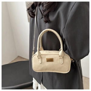 Detail of beige wrinkled PU leather boston bag with gold nameplate on a model