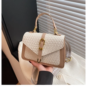 Detail of beige embossed woven texture leather handbag with gold metal hardware and strap