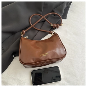 Close-up of brown oiled leather shoulder bag with gold lettering and knotted strap detail