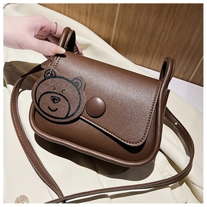 Detail of dark brown matte PU leather crossbody bag with a cute bear charm pendant