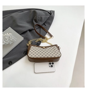 Close-up of brown monogram crossbody bag with gold floral buckle and chain strap