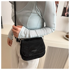 Détail du sac de selle plissé noir avec boucles argentées et texte de mode élégant