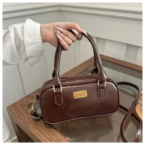 Detail of dark brown PU leather boston bag with golden logo plaque and zipper
