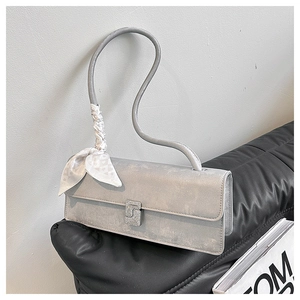 Detail of grey rectangular shoulder bag with unique curved handle and silk scarf decor