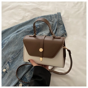Détail du sac bandoulière bicolore en cuir avec rabat marron et boucle dorée élégante