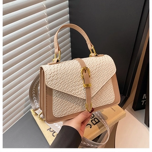 Detail of beige and brown crossbody bag with woven texture flap and wide patterned strap