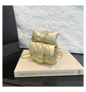Detail of champagne gold quilted mini bag with a large bow and elegant chain strap