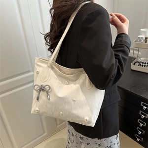Chic cream white tote bag with elegant pearls, silver bow charm, and textured finish
